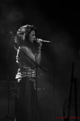 Photo en noir et blanc où une femme de profil chante devant un micro