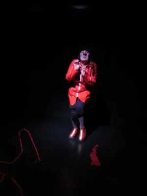 La clowne Véronique Martin débout sur une scène de théâtre sur fond noir