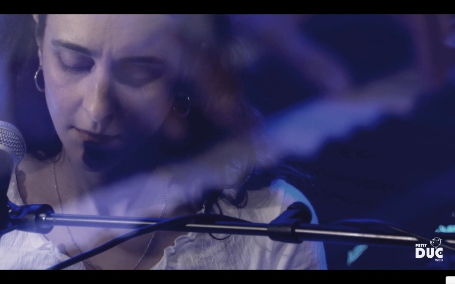 Une jeune femme, Cécile Grâce, devant un micro, elle regarde en bas, entourée d'une lumière bleue