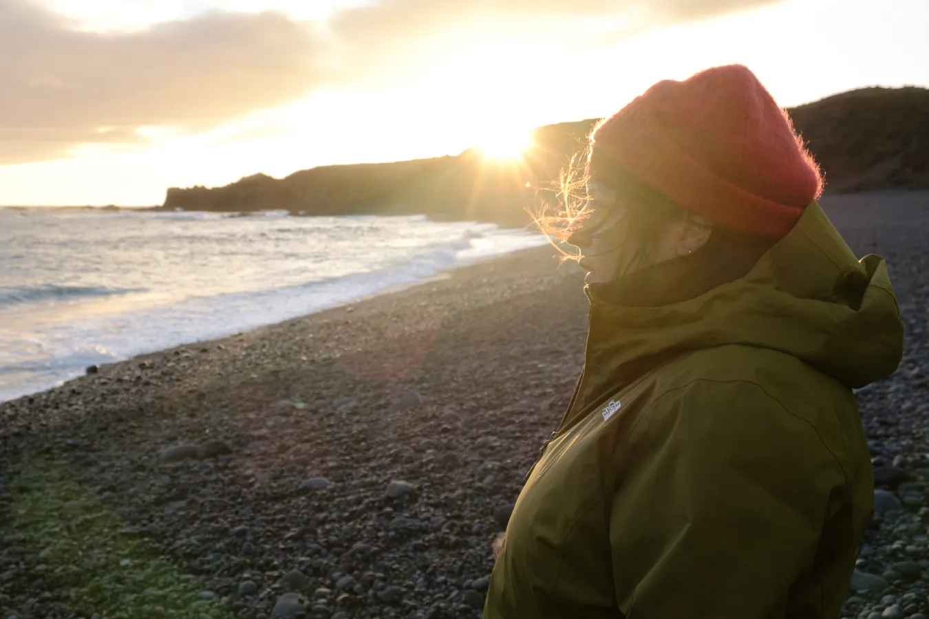 Photo en couleurs, une femme de profil qui regarde l'horizon et la mer devant elle